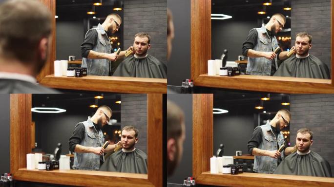 在理发店里，戴眼镜的理发师用剪子剪了胡子男人的头发。沙龙中的潮人发型设计和理发。用修剪器梳理头发。理