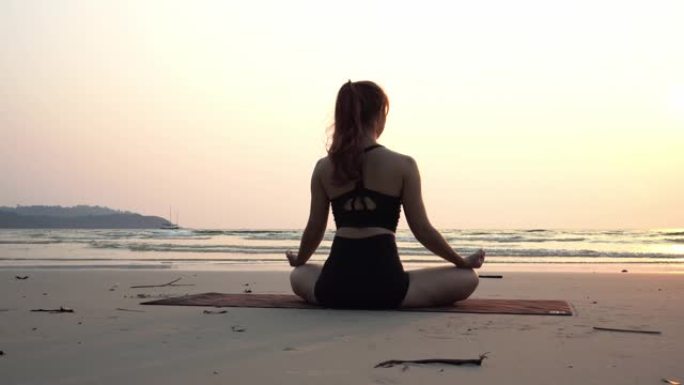背影女人练习瑜伽莲花姿势冥想暑假在海滩上感觉如此幸福和快乐，在泰国热带海滩旅行，度假和放松的概念