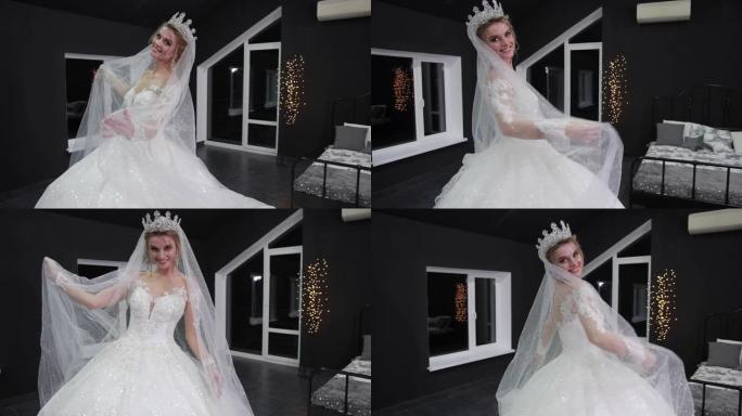 头上戴着皇冠的新娘在镜头前微笑着，双手戴着面纱。
