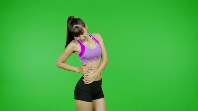 背部受伤，绿屏，锻炼，运动事故，受伤。适合年轻的亚洲体育女子在紫色的布在痛苦的锻炼在镜头前。