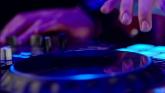 夜总会迪斯科派对Dj调音台控制器的特写。DJ手触摸按钮和滑块播放电子音乐。DJ手在乙烯基板上混合和刮
