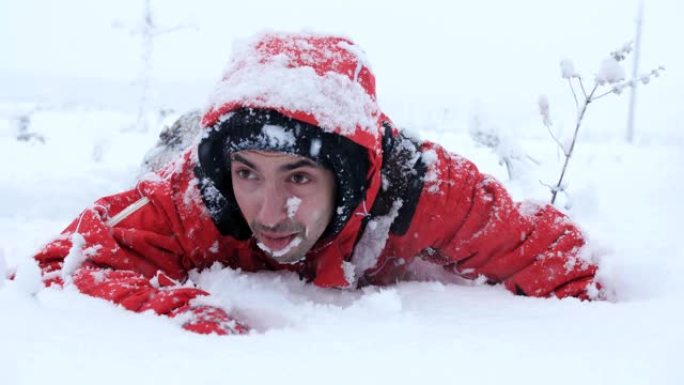 疲倦的旅行者或登山者正试图从雪山下走出来。一个在雪地里爬行的人。