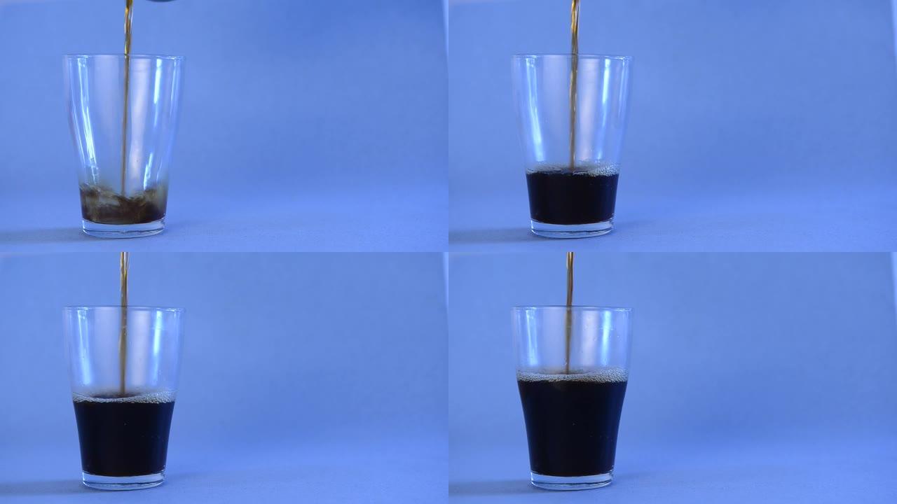 黑咖啡倒入孤立的蓝色背景上的透明玻璃杯中