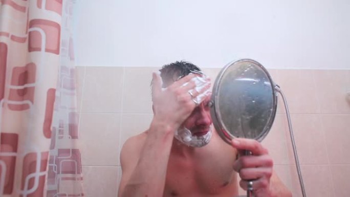 浴室里的一个男人正在脸上撒上剃须泡沫。