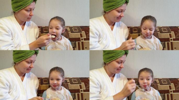 一个女人在厨房里喂一个小女孩燕麦片吃晚饭