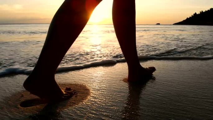 年轻女子在美丽的日落下走在海滩上