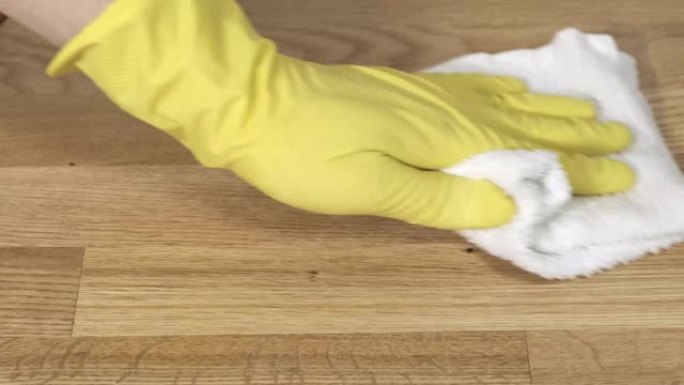 女性双手戴着黄色橡胶手套清洁公寓。洗涤镶木地板。