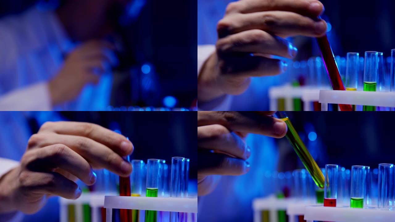 倾斜无法辨认的散焦男性科学家的特写镜头，看着显微镜，在实验室里用多色液体试管