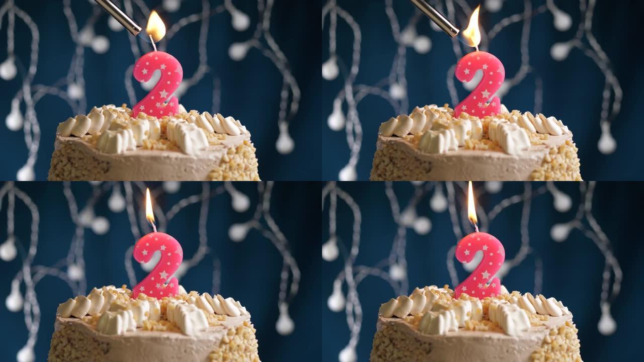 蓝色背景上有2个数字粉色蜡烛的生日蛋糕。蜡烛着火了。慢动作和特写视图