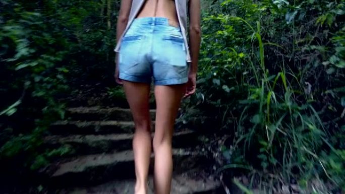 背面女孩在茂密的森林中走上旧的石阶