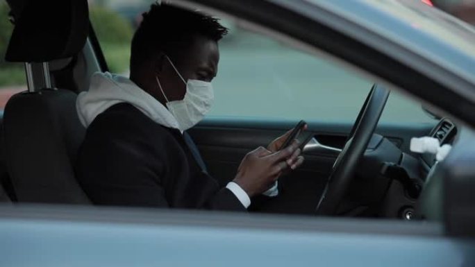 戴着外科口罩的非裔美国人在汽车上阅读新闻