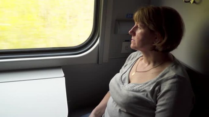 年轻女子坐在窗边的火车车厢里