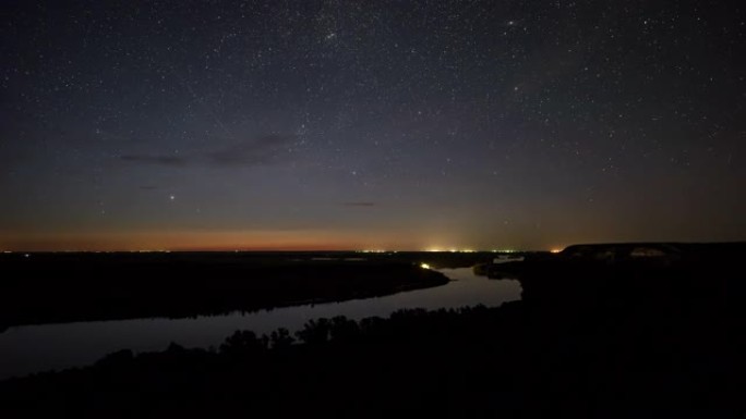 夜景风景。夜色的星空和闪亮的星星映照在河中。星径滚动。从夜晚到黎明平稳过渡的时间流逝。静态空中俯视图