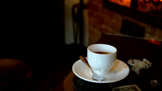 咖啡馆或带壁炉的餐厅的桌上摆着一杯咖啡。