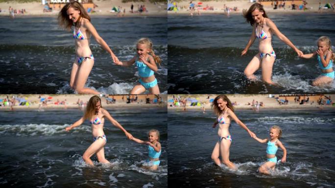 穿着比基尼的妈妈和女儿女孩在海浪中奔跑
