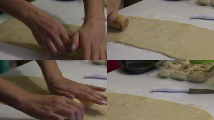 一个女人为朱砂卷面团。桌子上撒了面粉。附近是一个装有面包的容器，用于烘烤。