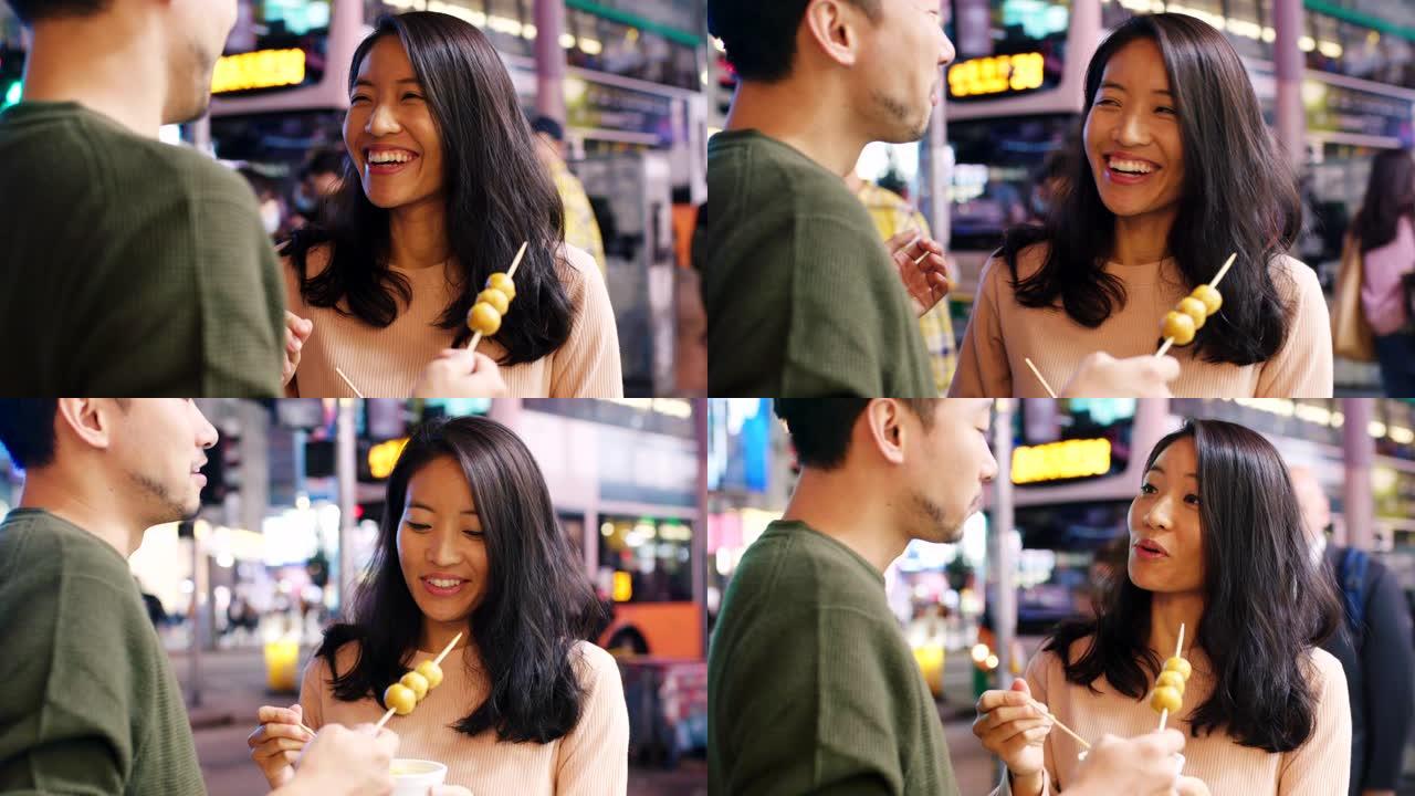 SLO MO手持特写镜头，一对年轻夫妇在吃街头美食