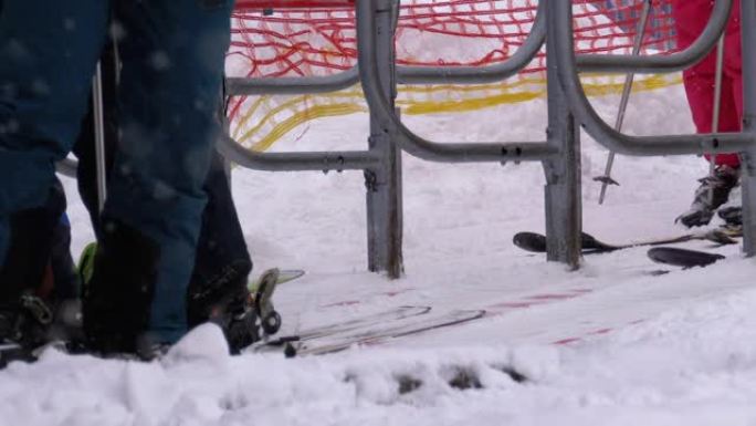 滑雪者通过滑雪缆车的旋转栅门。滑雪椅的入口举着滑雪者。慢动作