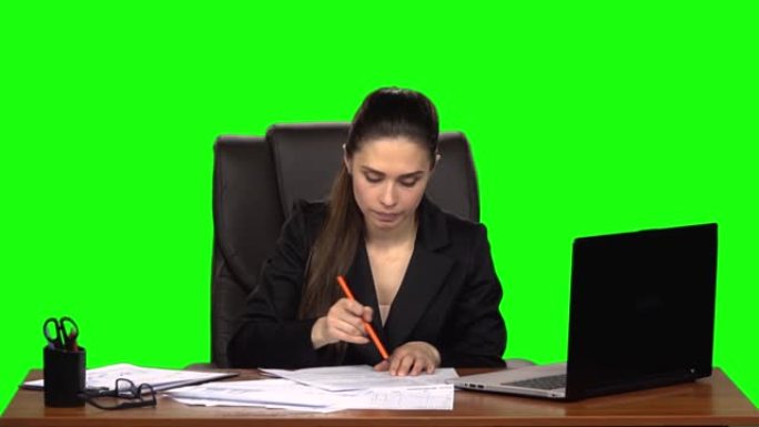 紧张的女人读文件，把写的东西划掉，把皱巴巴的纸从桌子上扔了出去。绿屏。慢动作
