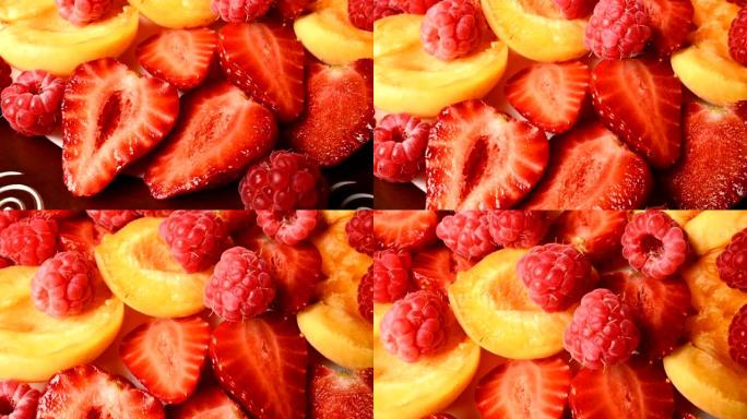 盘子上杏子旁边切成薄片的红色草莓和覆盆子的特写镜头。现场摄像机。美味有益健康的饮食和素食的概念。