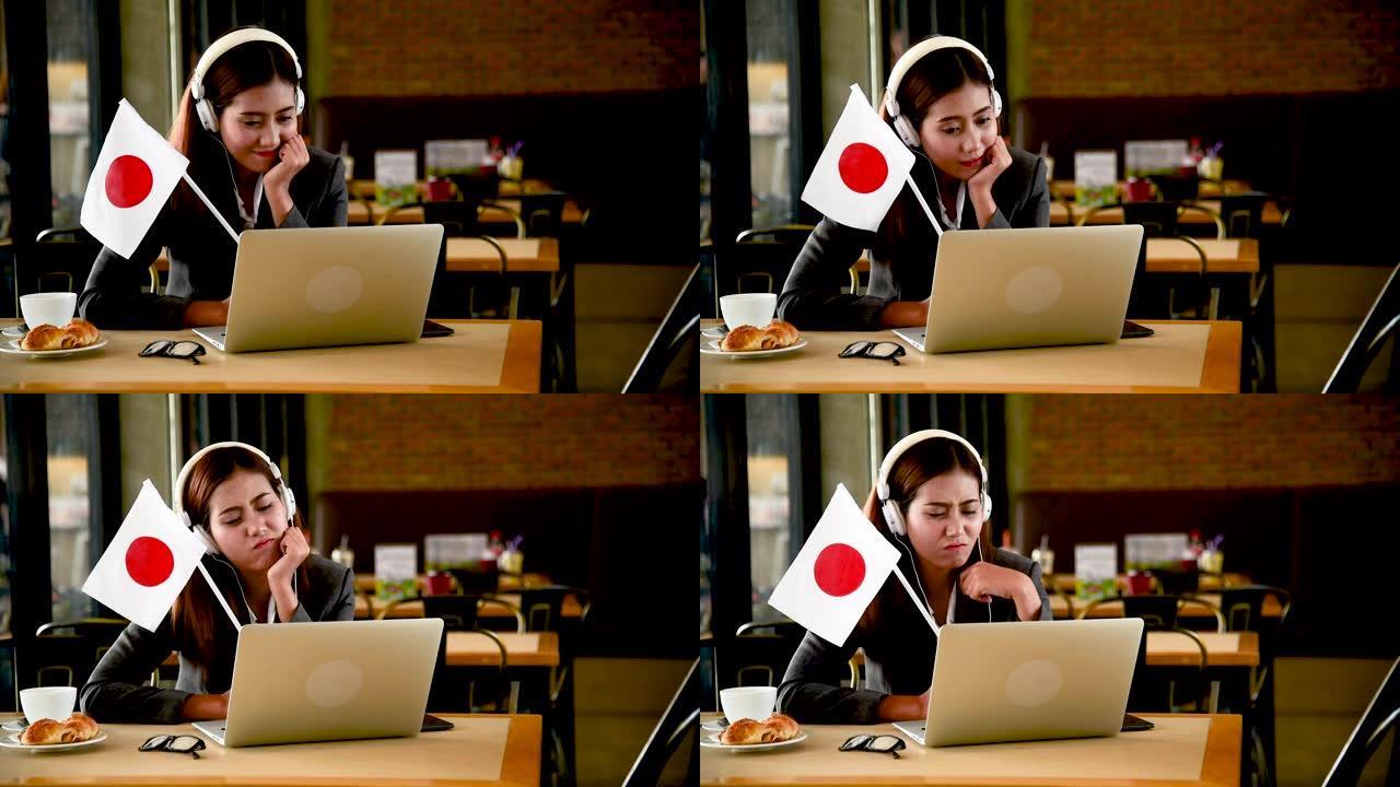 商业女性从笔记本电脑上观看在线体育，挥舞着日本国旗欢呼日本。