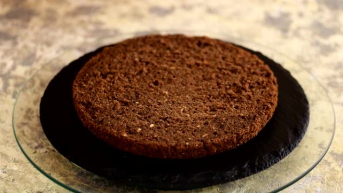 无法辨认的女性糖果手在厨房用硅烹饪刷用甜咖啡浸泡海绵蛋糕，特写。