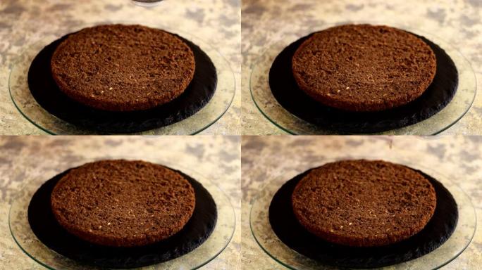 无法辨认的女性糖果手在厨房用硅烹饪刷用甜咖啡浸泡海绵蛋糕，特写。