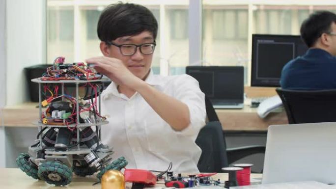 亚洲男子工程师在实验室组装和测试机器人手臂反应。建筑师设计电路使机器和机器人的技术和智能同步。