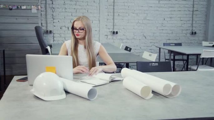 年轻的现代女商人正在使用笔记本电脑进行工程项目新头盔