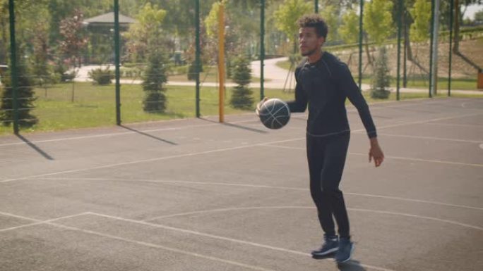 年轻英俊的非洲裔美国男子篮球运动员在球场户外将球扔进篮筐的特写肖像