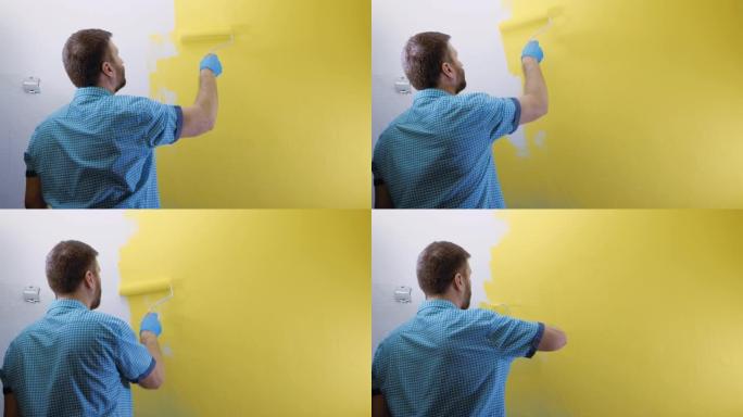 男人用黄色的右手用滚筒画白色的墙。他穿着格子蓝色衬衫和手套。慢动作和中等镜头