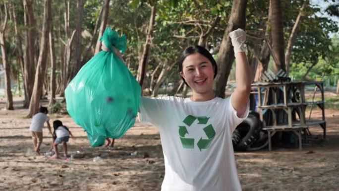 亚洲女人从海滩上展示垃圾袋。海滩的清洁度和环境。安全生态和循环利用理念。慢动作