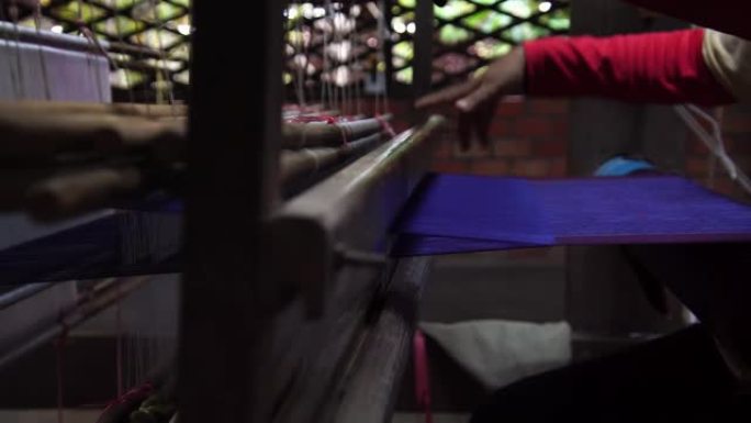 女人编织手工丝绸衣服。用传统工具手工制作丝绸。手摇织机行业。