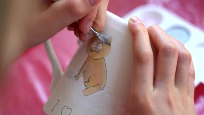 儿童在陶器车间画杯子。画一只猫。
