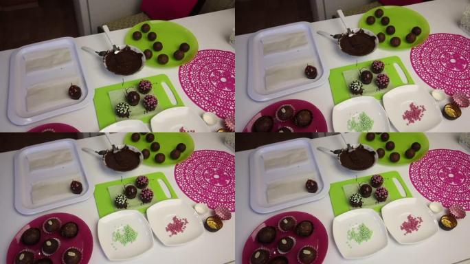 工作表面上是巧克力海绵蛋糕球。用洒水装饰。蛋糕土豆的空白。盘子旁边是蛋糕坯料，液体巧克力和彩色洒。