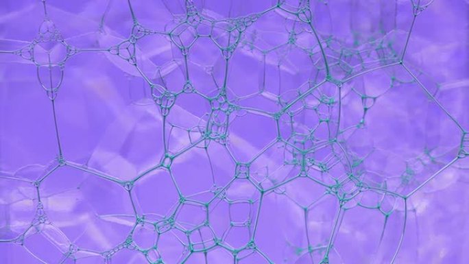 彩色肥皂泡沫与爆裂气泡背景。摘要生物结构，大分子模式。蓝色墨水填充了大量在液体中形成的紫色气泡。自然
