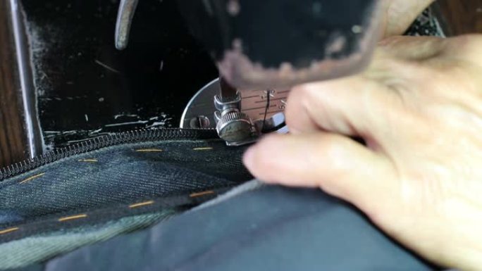 用旧机器缝制牛仔裤的手指。