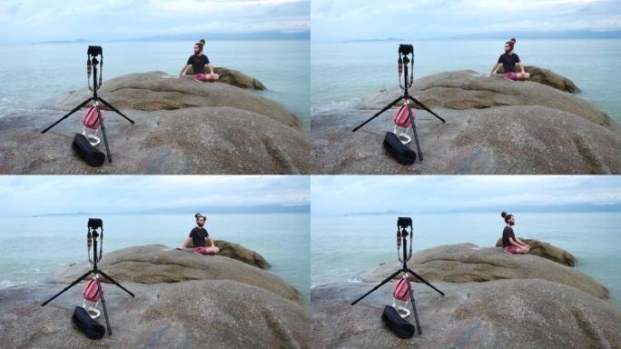 男性视频记录器Yogi为海上岩石上的社交网站拍摄视频
