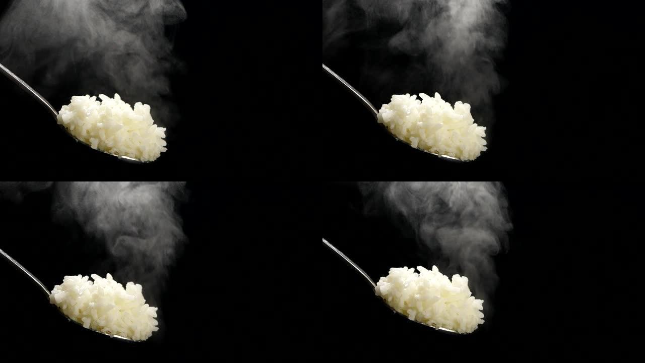 在黑色背景上慢动作的勺子上的米饭
