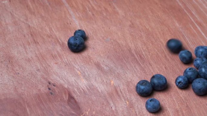 蓝莓在棕色木板上滚动。