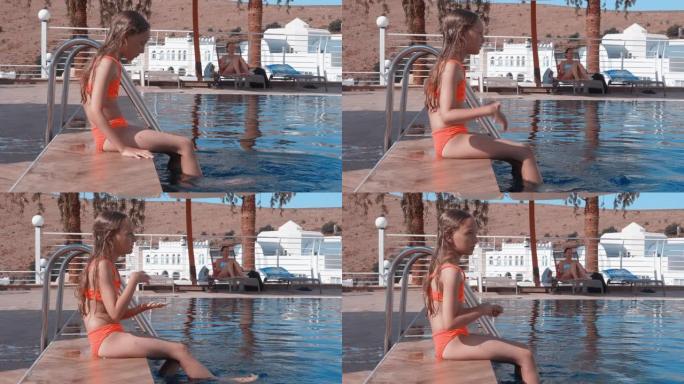 在度假酒店，十几岁的女孩坐在泳池边缘，将双腿浸入水中。年轻女孩在夏季酒店用脚在游泳池里泼水。旅游女孩