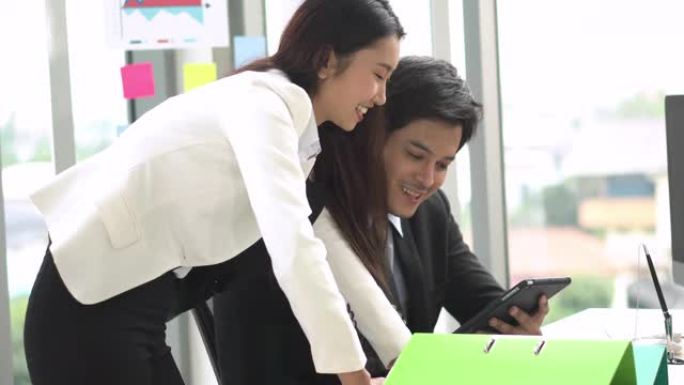 年轻的亚洲女商人使用平板电脑与团队分享想法