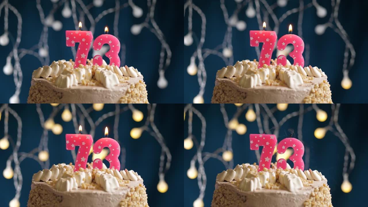 蓝色背景上有73号粉色蜡烛的生日蛋糕。蜡烛吹灭了。慢动作和特写视图