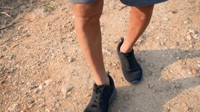 在乡村的田野上，在日落背景上慢跑的亚洲老人的腿特写。医疗保健概念。