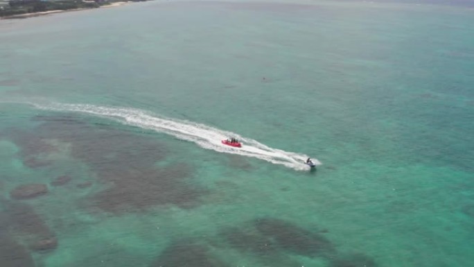喷气式飞机拖着香蕉浮桥漂浮在日本冲绳的局部珊瑚礁上