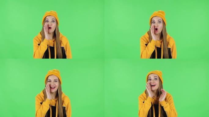 戴着黄色帽子的现代女孩的肖像尖叫着呼唤某人。绿屏