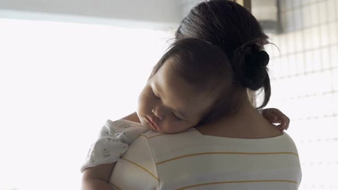 生病的女婴睡在母亲的肩膀上
