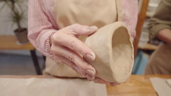 匿名女士的手在陶艺工作室打磨粘土碗的表面