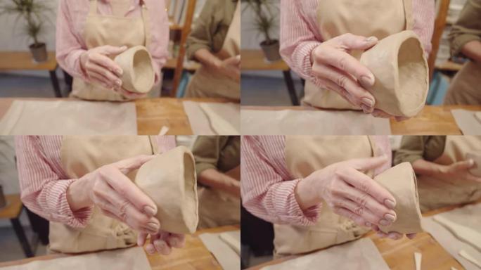 匿名女士的手在陶艺工作室打磨粘土碗的表面
