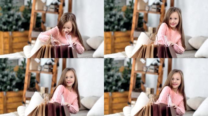 兴奋的小可爱女孩打开圣诞礼物包装袋获得金色闪光球